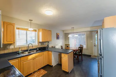 a kitchen with wooden cabinets and a sink and a refrigerator at Bright 3BR Upper Suit, 23 min to Jasper NP in Hinton