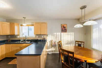 a kitchen with a wooden table and a dining room at Bright 3BR Upper Suit, 23 min to Jasper NP in Hinton