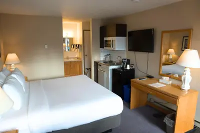a bedroom with a bed and a desk and a kitchen at Chalet Inn in Kitimat