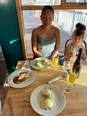 a woman and child sitting at a table with plates of food at Aurora Bayside Inn in Yellowknife