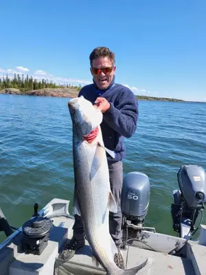 a man holding a fish on a boat at Aurora Bayside Inn in Yellowknife