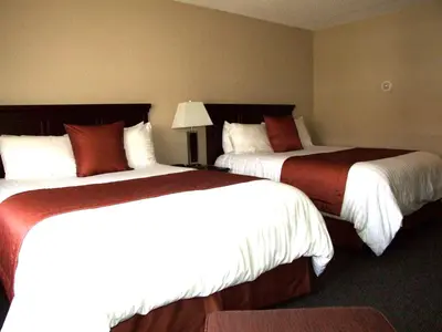 two beds in a hotel room with white and red at Lakeland Inn Hotel in Cold Lake