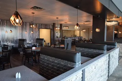 a restaurant with a bar with tables and chairs at Lakeland Inn Hotel in Cold Lake