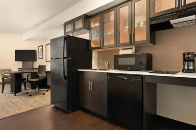 a kitchen with a black refrigerator and a desk at Park Inn by Radisson, Calgary Airport North, AB in Calgary