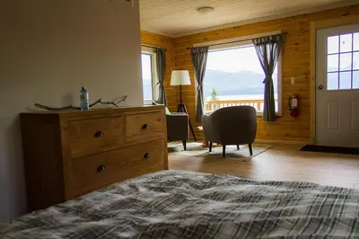 a bedroom with a bed and a dresser and a window at Southern Lakes Resort in Tagish