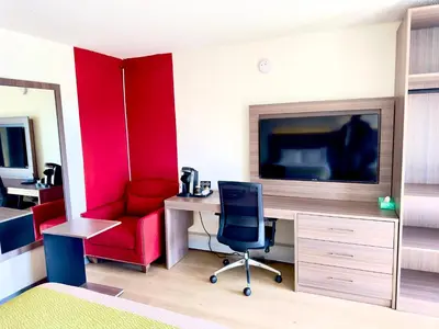 a room with a desk and a chair and a tv at Westport Inn in Grande Prairie