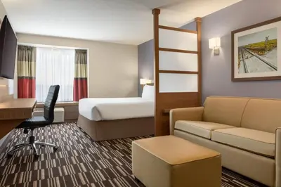 a hotel room with a bed and a couch and a bedroom at Microtel Inn & Suites by Wyndham Bonnyville in Bonnyville