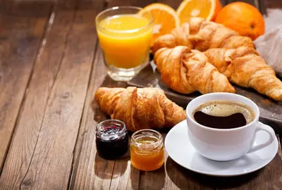 a table with a cup of coffee and croissants and orange juice at Pomeroy Inn and Suites Vermilion in Vermilion