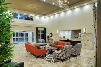 a living room with orange chairs and a table at Pomeroy Inn and Suites Vermilion in Vermilion