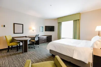 a hotel room with a bed and a desk and a table at Candlewood Suites West Edmonton - Mall Area by IHG in Edmonton