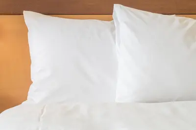 a bed with white sheets and pillows on it at Candlewood Suites West Edmonton - Mall Area by IHG in Edmonton