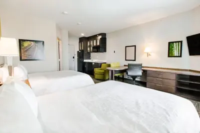 a hotel room with two beds and a desk at Candlewood Suites West Edmonton - Mall Area by IHG in Edmonton