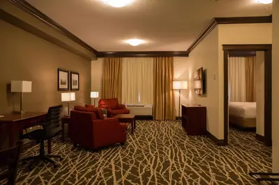 a hotel room with a desk and a living room at Chateau Nova Peace River in Peace River