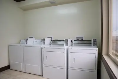 three washers and dryers sitting in a room at Chateau Nova Peace River in Peace River