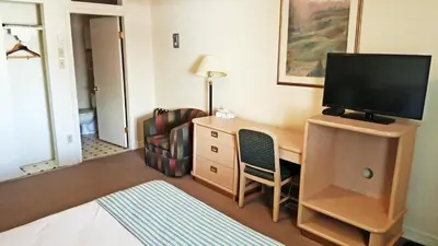 a room with a desk with a television and a chair at Badlands Motel in Drumheller