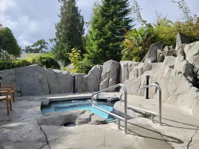 a swimming pool with a bench and a rock wall at Pacific Shores Resort & Spa in Nanoose Bay