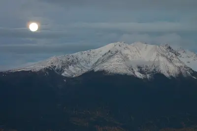 a snow covered mountain with the moon in the sky at Smithers Driftwood Lodge in Smithers