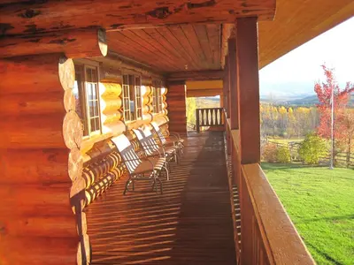a porch of a log cabin with chairs on it at Smithers Driftwood Lodge in Smithers