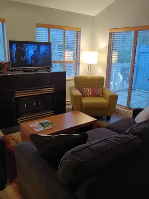 a living room with a couch and a tv and a fireplace at Tyndalstone Lodge 3 Bedroom in the Heart of Village North Whistler in Whistler