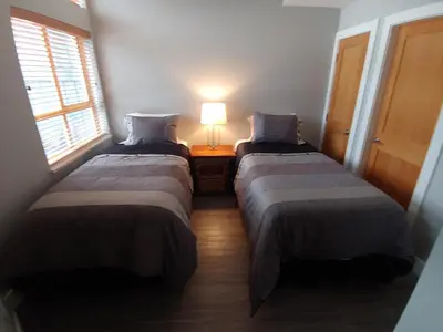 two beds in a room with a lamp on a table at Tyndalstone Lodge 3 Bedroom in the Heart of Village North Whistler in Whistler