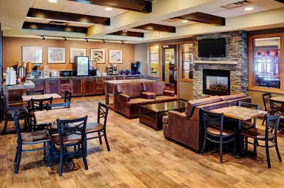 a living room with tables and chairs and a fireplace at Lakeview Inns & Suites - Fort Saskatchewan in Fort Saskatchewan