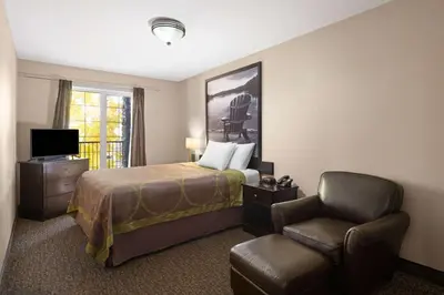 a hotel room with a bed and a chair at Super 8 by Wyndham Fort McMurray in Fort McMurray