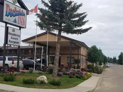a building with a tree in front of it at Dockside Inn in Cold Lake