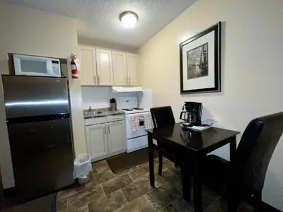 a kitchen with a black refrigerator and a table at Dockside Inn in Cold Lake