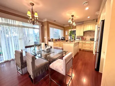 a kitchen and dining room with a glass table and chairs at Vancouver Luxury Homestay in Richmond