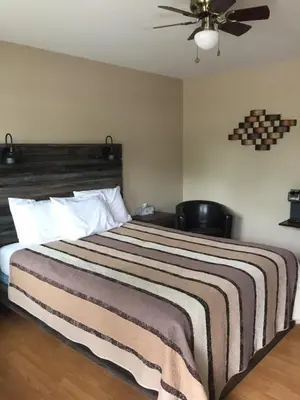 a bedroom with a large bed with a ceiling fan at Kacee's Northern Suites in Fort Nelson