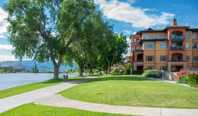 a large apartment building with a grassy yard next to a lake at Watermark Beach Resort in Osoyoos