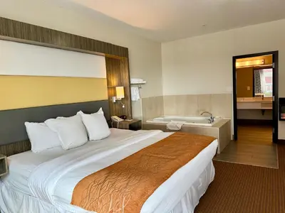 a hotel room with a large bed and a bath tub at Southfort Inn in Fort Saskatchewan