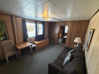 a living room with a couch and a table and a desk at Airport Chalet in Whitehorse