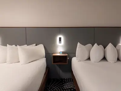 two beds with white pillows in a hotel room at Carriage House Hotel and Conference Centre in Calgary