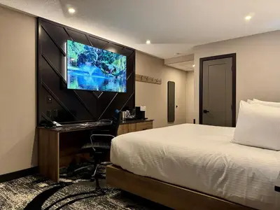 a hotel room with a bed and a flat screen tv at Carriage House Hotel and Conference Centre in Calgary