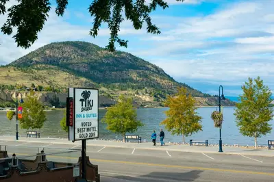 a sign in front of a lake with a mountain at Tiki Shores Inn & Suites in Penticton