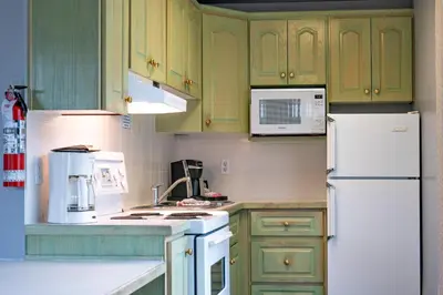a kitchen with green cabinets and a white refrigerator at Tiki Shores Inn & Suites in Penticton