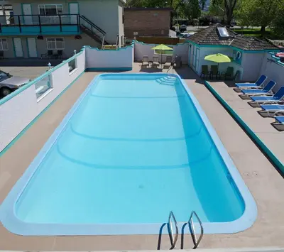 a large blue swimming pool with a pair of sandals in front at Tiki Shores Inn & Suites in Penticton