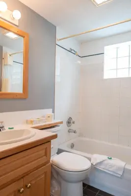 a bathroom with a tub and a toilet and a sink at Tiki Shores Inn & Suites in Penticton