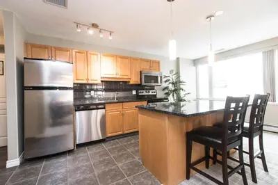 a kitchen with wooden cabinets and a stainless steel refrigerator at Canterra Suites Hotel in Edmonton