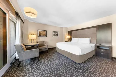a hotel room with a bed and a chair at Best Western Plus Banff International Lodge in Banff
