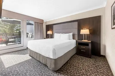 a hotel room with a large bed and a balcony at Best Western Plus Banff International Lodge in Banff