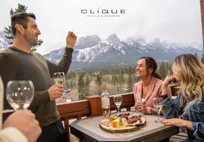 a group of people sitting around a table with wine glasses at Falcon Crest Lodge by CLIQUE in Canmore