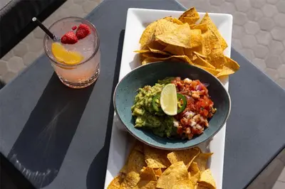 a plate of guacamole and chips and a drink at Doubletree By Hilton West Kelowna in West Kelowna