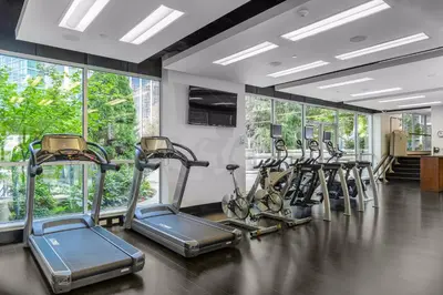 a gym with a row of tread machines in a room at Loden Vancouver in Vancouver