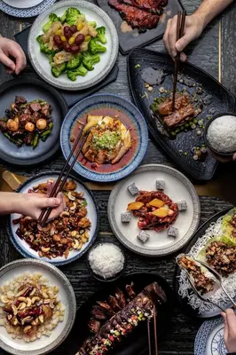 a table full of plates of food with people holding chopsticks at Paradox Vancouver in Vancouver
