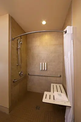 a bathroom with a shower with a bench in it at Bayview Hotel in Courtenay