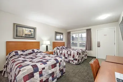 a hotel room with two beds and a table at Guest House Inn & Suites in Edson