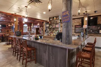 a bar in a restaurant with wooden chairs at Guest House Inn & Suites in Edson