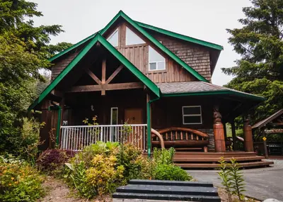 a small house with a porch and a white fence at Wild Coast Wilderness Resort in Port Renfrew